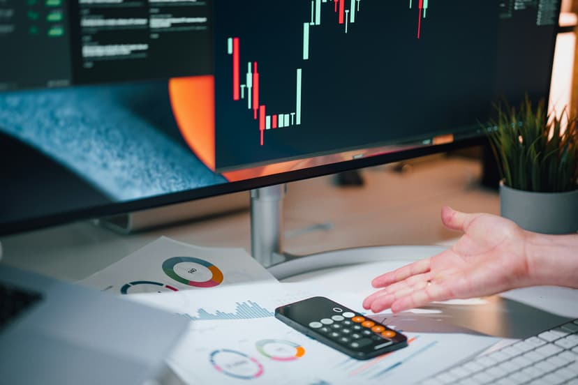 Hand pointing at a calculator and complex financial chart and graphs