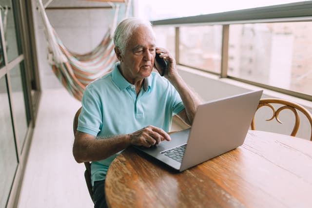 Elderly man talking on the phone to a precious metals specialist about preserving wealth with gold
